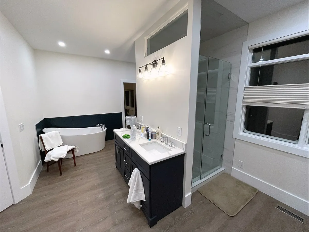 Bearspaw ensuite with freestanding tub, dark vanity and glass shower