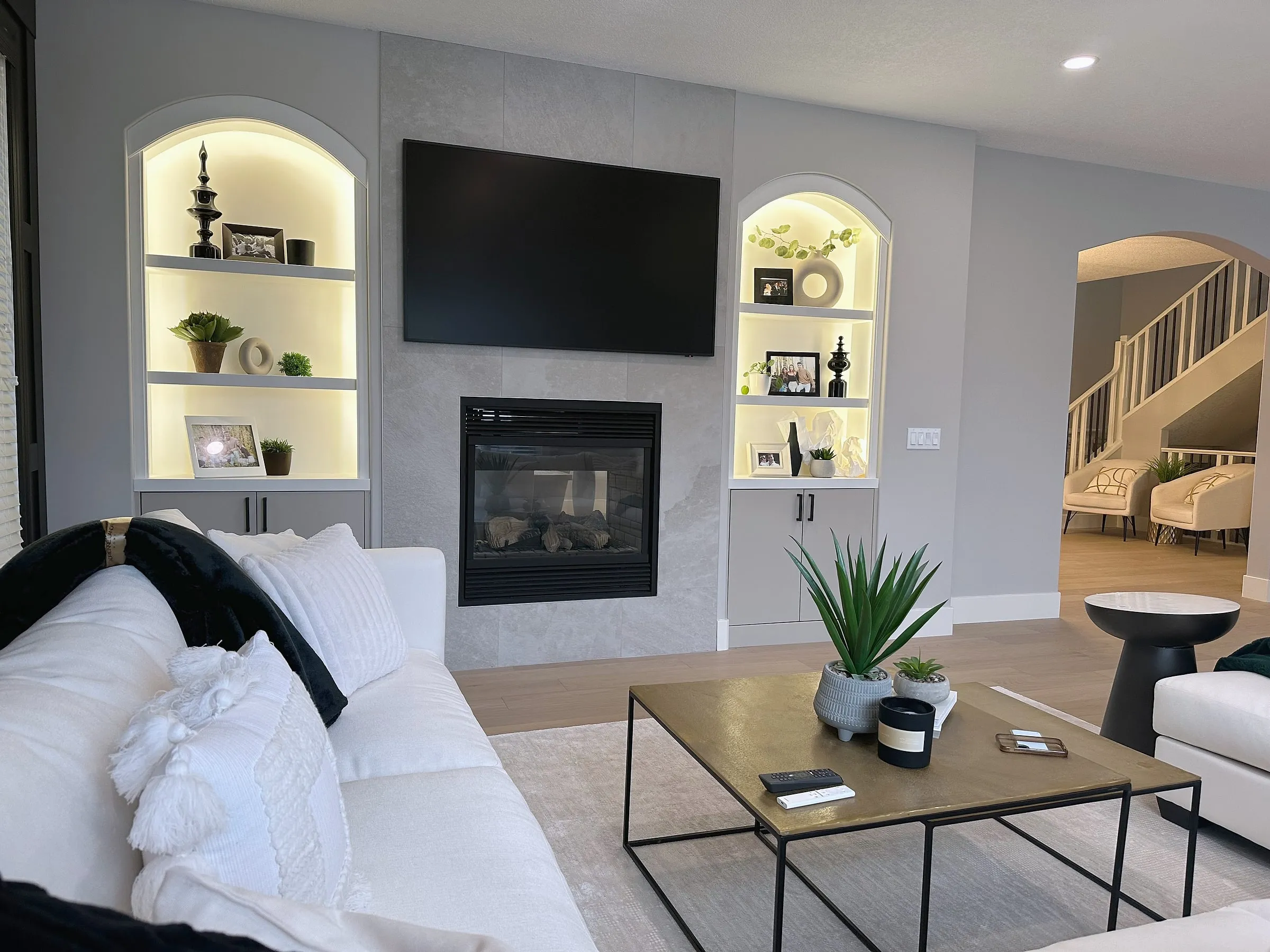 Willows of Wentworth living room renovated by iRenos in Calgary, with a full-height fireplace surround and illuminated arched shelves