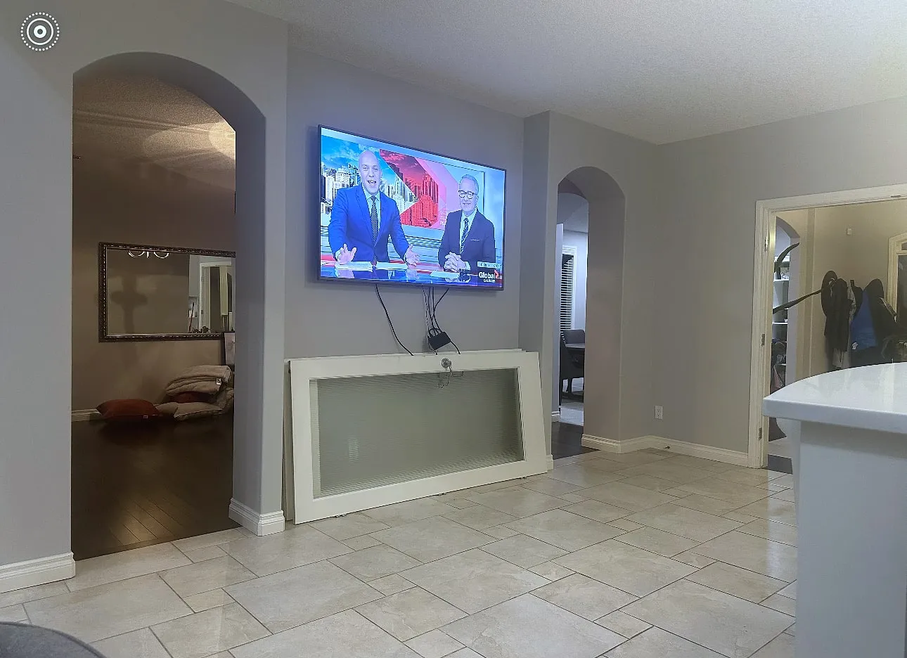 Willows of Wentworth living room before renovation, with open arches beside the TV wall and tile flooring
